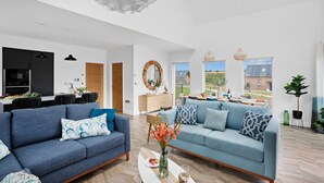 A spacious living room with two sofas, a coffee table, and a dining area with a view of the countryside. - 5 The Vista, Willingcott Nr Woolacombe - Hot tub/ Pet friendly/ On-site pool / Ecohome (Woolacombe)