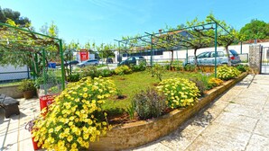 Ein Garten mit gelben Blumen, einer grünen Pergola und einem gepflasterten Weg.
