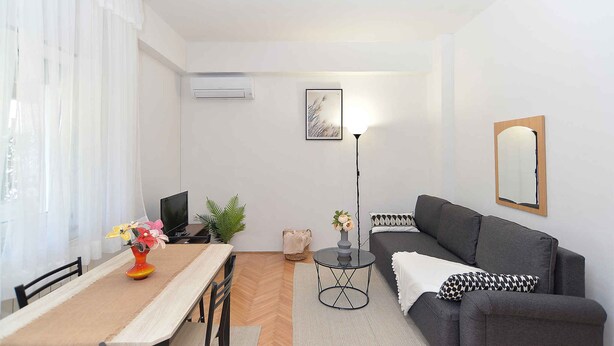 A modern living room with a sofa, a dining table, and a TV. - Holiday apartment with air conditioning (Banjole)