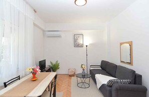 A modern living room with a sofa, a dining table, and a TV. - Holiday apartment with air conditioning (Banjole)