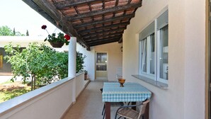 A balcony with a checkered tablecloth, a chair, and hanging flowers. - Holiday apartment with air conditioning (Banjole)