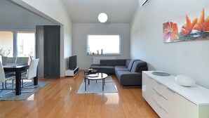 A modern living room with a sofa, a dining table, and a TV. - Holiday apartment with sea view and air conditioning (Banjole)