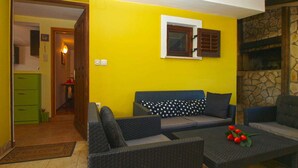 Une pièce avec un mur jaune, un canapé, une table et une cheminée en pierre.