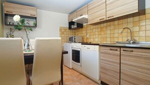 Une cuisine avec des meubles de rangement en bois, un four à micro-ondes, un four traditionnel et un lave-vaisselle.