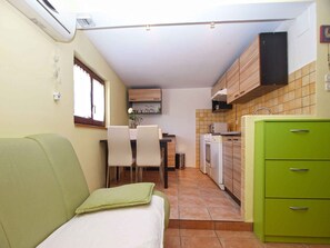 Uma cozinha compacta com área de refeições, um armário verde e uma janela.