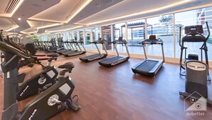 A modern gym with multiple treadmills, stationary bikes, and a rowing machine. - Stunning Studio With Balcony in Arjan (Dubai)