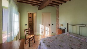 A bedroom with a bed, a chair, a table, and a wardrobe. - Appartamento Ampio nel Borgo Medioevale (colle di val d'elsa)