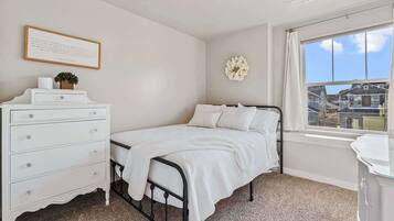 Een slaapkamer met een bed, een dressoir, een raam met uitzicht en een decoratie aan de muur.