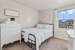 Ein Schlafzimmer mit Bett, Schminktisch, Fenster mit Blick und Wanddeko.