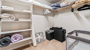 A neatly organized closet with shelves, hanging space, and a small fan.