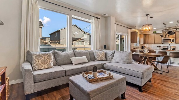 A modern living room with a sectional sofa, a dining area, and a kitchen.