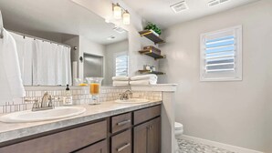 A modern bathroom with a double sink vanity, a large mirror, and built-in shelves.