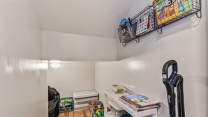 A small, well-organized storage area with shelves, bins, and a vacuum cleaner.