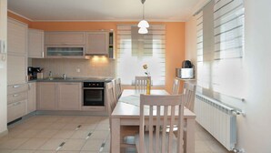A modern kitchen with a dining area, featuring cabinets, a microwave, and a table with chairs.