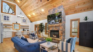 Una sala de estar acogedora con chimenea de piedra, techo de madera y un sofá azul.