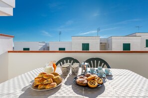 A table set with pastries and drinks on a balcony with a clear sky and buildings in the background. - 3712 Blusea Beach Apt - Primo Piano by Barbarhouse (Manduria)