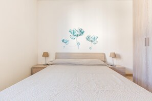 A bedroom with a large bed, two bedside tables, and a wall-mounted lamp. - 3712 Blusea Beach Apt - Primo Piano by Barbarhouse (Manduria)