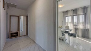 Un couloir avec un mur recouvert de miroirs, une porte et une vue sur un coin repas comprenant une table et des chaises.