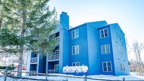 A multi-story building with a blue exterior, a visible chimney, and a sign indicating a restaurant. - Salty Peaks - Slopeside C301 (Tucker County)