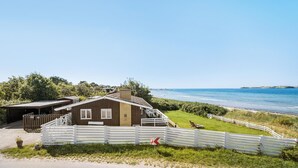 Ein Küstenhaus mit einer Terrasse mit Meerblick, einem eingezäunten Garten und freiem Blick auf die Küste.