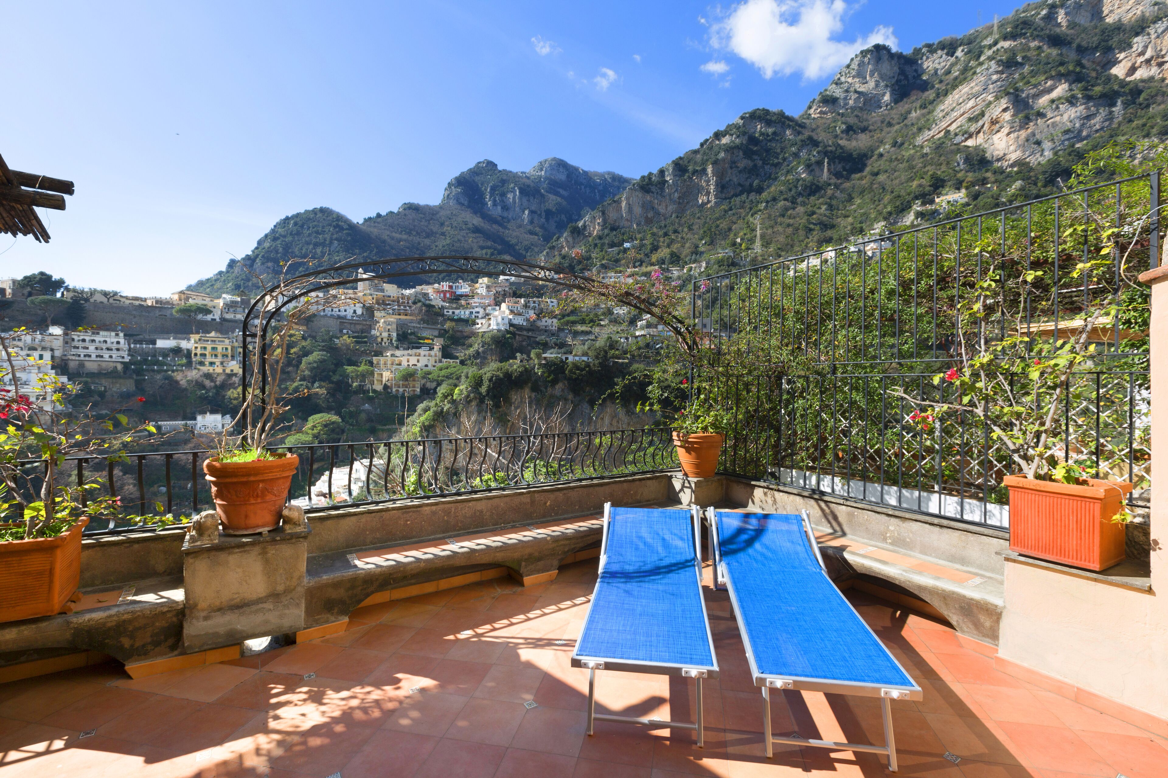 Une terrasse avec une table de ping-pong, des plantes en pot et une vue sur une ville située dans un paysage montagneux.