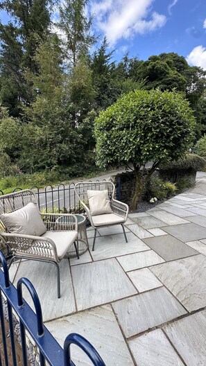 An outdoor seating area with wicker chairs and a stone wall.