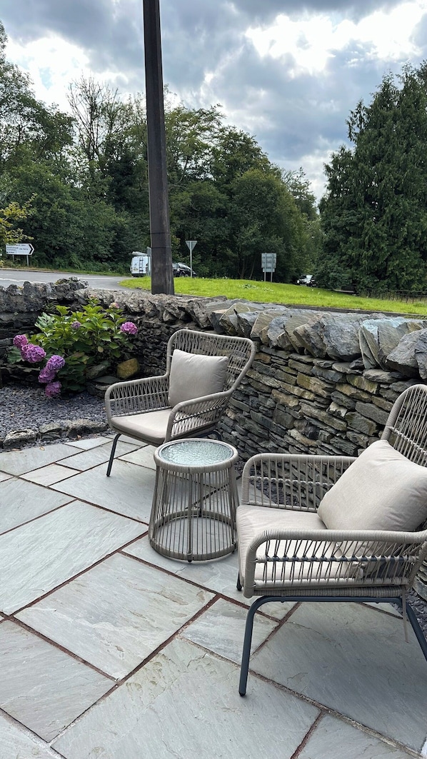 An outdoor patio area with wicker furniture and a stone wall.