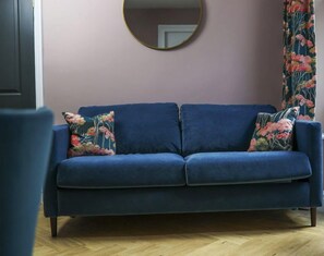 Versatility meets comfort in Wainwright's living room, featuring a luxurious Warwick velvet-covered sofa that effortlessly transforms into a full-size double bed, offering flexibility for accommodating up to six guests, perfect for a family getaway.