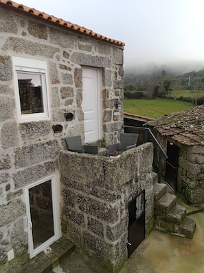 A stone building with a white door, a window, and a small balcony. - Cottage Aldeia Da Serra - Historic Areas of Portugal (Celorico da Beira)