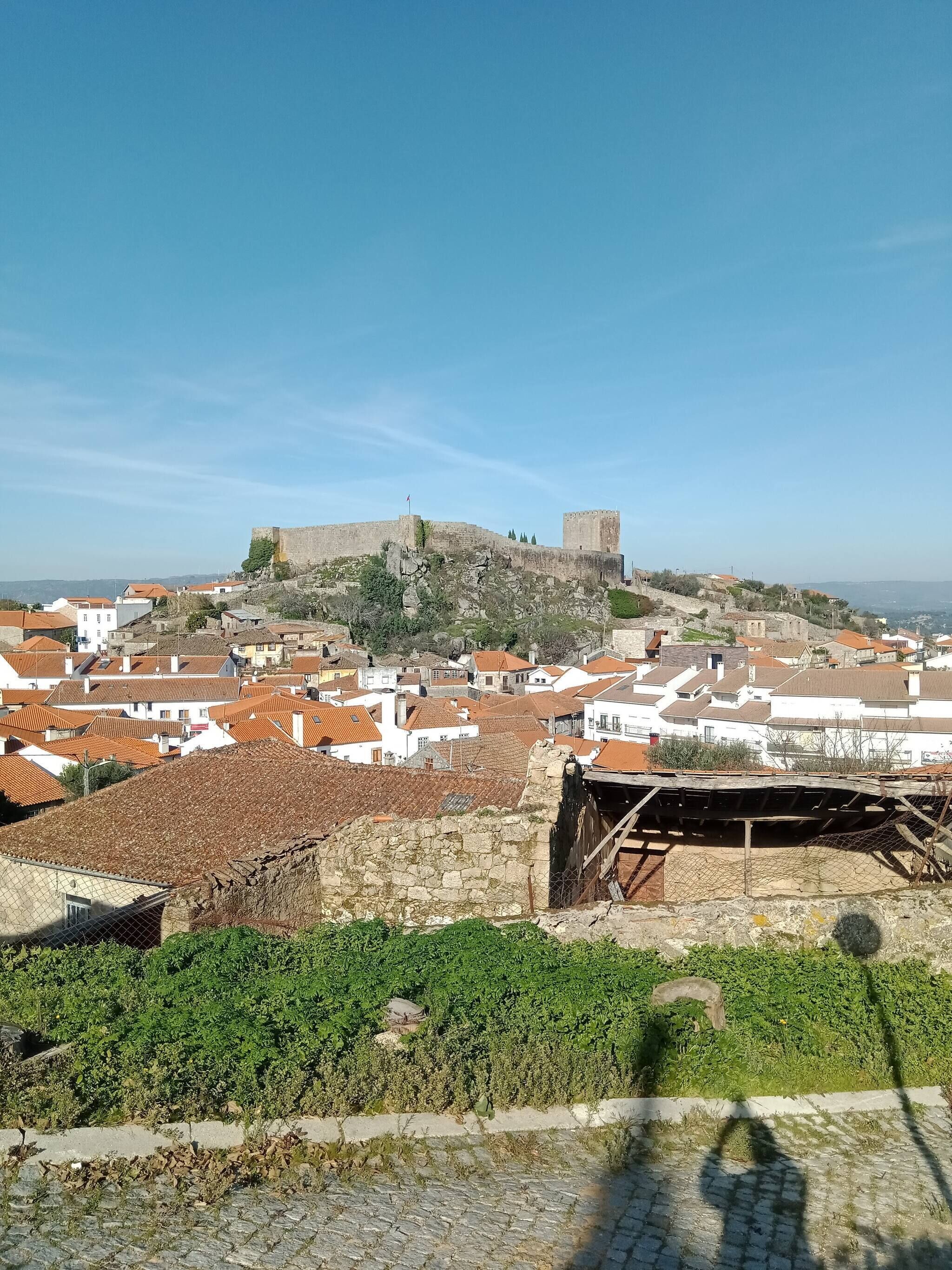 A historic town with stone buildings, a prominent fortification on a hill, and cobblestone streets.