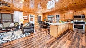 A spacious living room with a fireplace, a dining area, and a kitchen with wooden cabinets and stainless steel appliances. - 5BD: Prime Pigeon Forge with 2 Hot Tubs, Pool Table, Theater, Arcade and 3 Decks (Pigeon Forge)