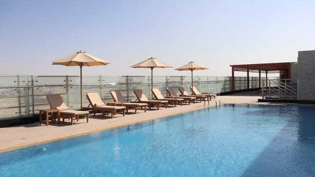 Una piscina en la azotea con sillones de descanso y sombrillas.