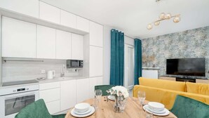 A modern kitchen with white cabinets, a microwave, and a dining area with a wooden table set for four.