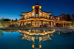 A multi-story hotel with a pool in front, featuring a modern architectural design with balconies and outdoor seating areas.