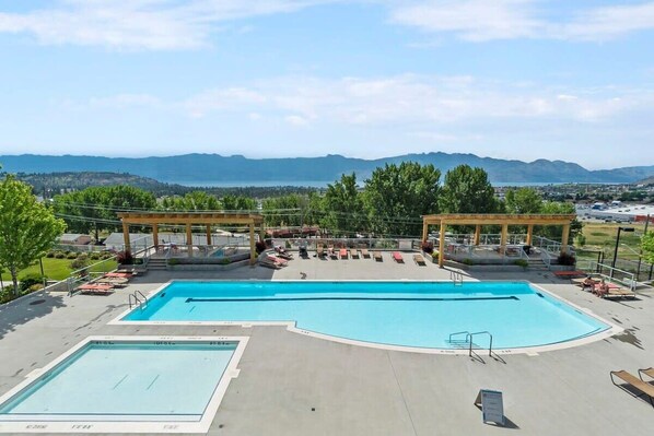 A swimming pool with two separate sections, a covered seating area, and a view of distant mountains.
