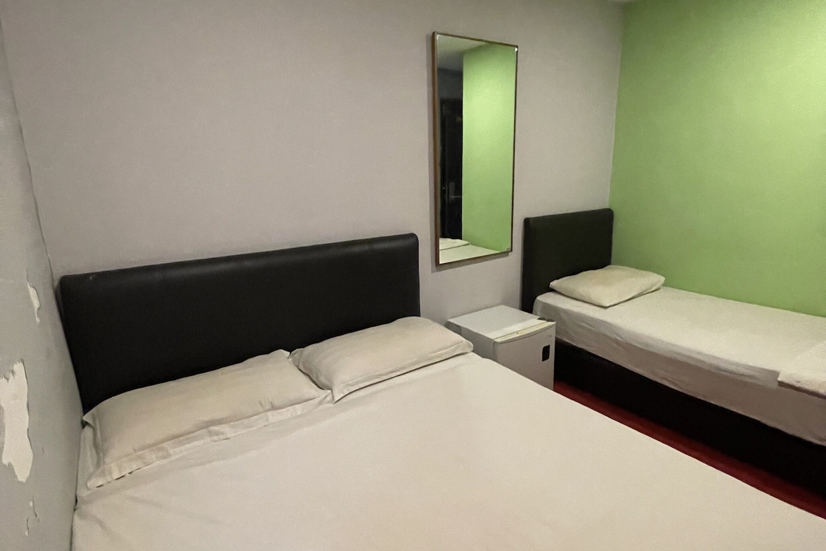 A hotel room with a large bed, a smaller bed, a nightstand, and a mirror on the wall.