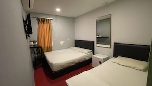 Habitació d'hotel amb dos llits, una taula, una cadira, un televisor i un mirall.