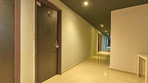 Un passadís amb una porta tancada, una banca blanca i un sòl de rajoles.