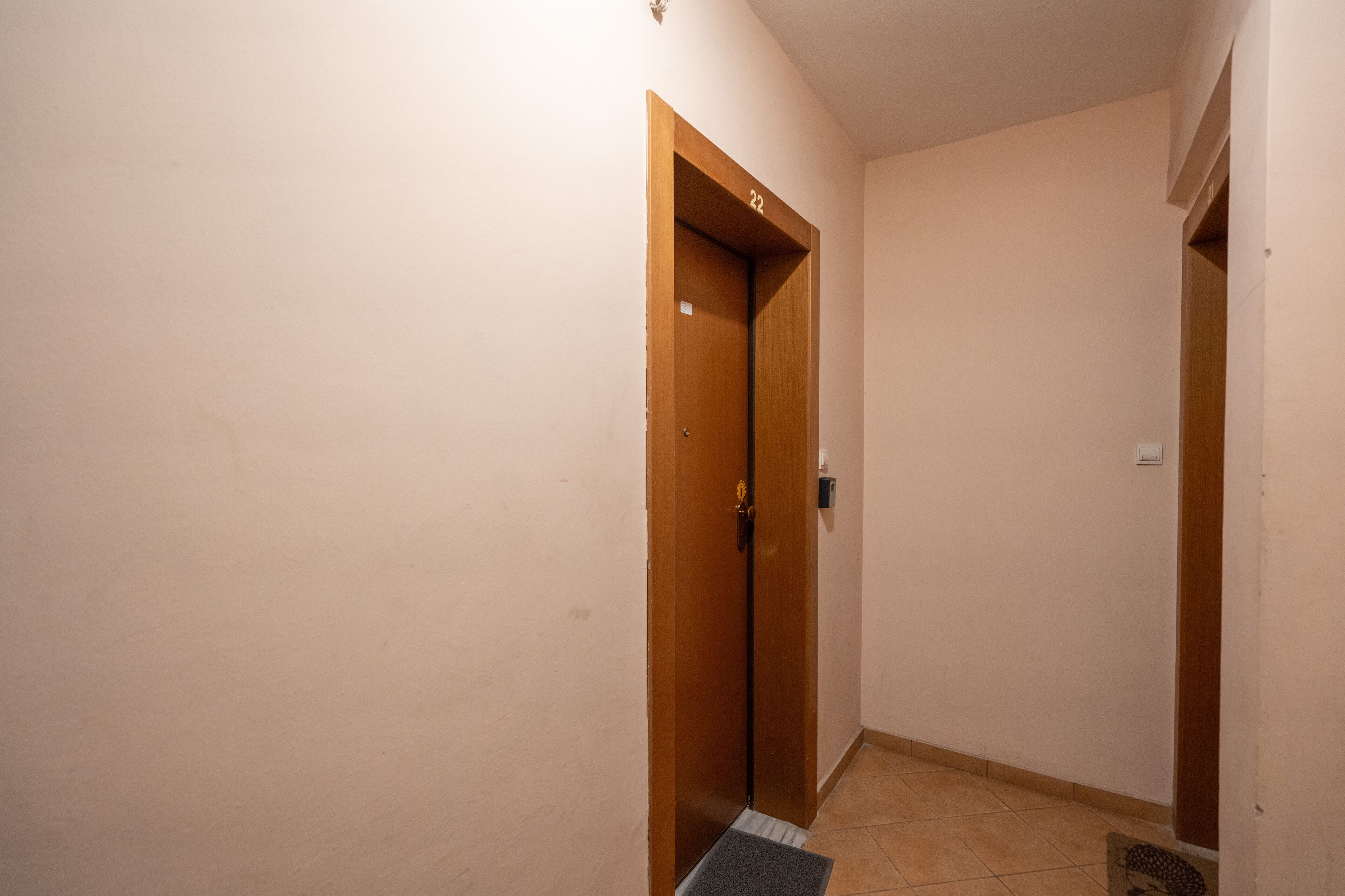 A narrow hallway with a wooden door marked with the number 22.