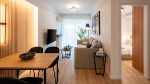 A modern living room with a wooden dining table, a sofa, and a TV. - Chic and Lavish Apartment in Athens (Kallithea)