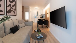 A modern living room with a sofa, a coffee table, and a flat-screen TV mounted on the wall. - Chic and Lavish Apartment in Athens (Kallithea)