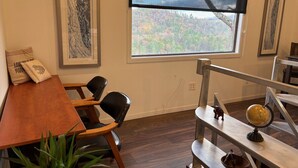 A room with a wooden table, two black chairs, a window with a view of a forest, and a globe on a shelf. - Eaglewatch Mountaintop Cabin (Bryson City)