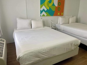 Une chambre d’hôtel avec deux lits, une table de chevet, un téléphone fixé au mur et un élément décoratif mural.