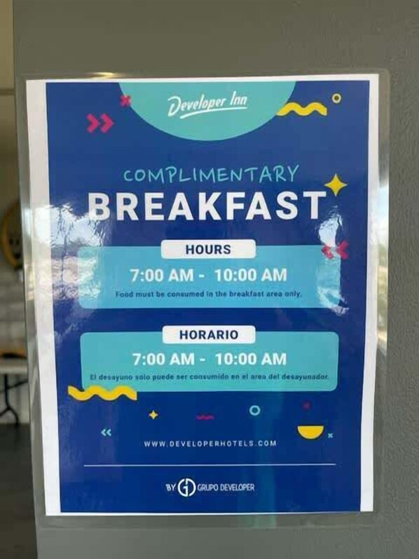 A complimentary breakfast sign at Developer Inn, stating hours from 7:00 AM to 10:00 AM.