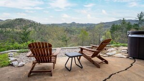 Un patio con due poltrone Adirondack e un tavolino, affacciato su un paesaggio montano.