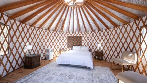 Una camera in stile yurta con un letto, due sedie, un tavolino e una ventola a soffitto.