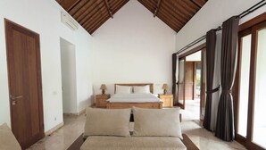 A bedroom with a wooden ceiling, a large bed, bedside tables, a sofa, and a view through a glass door. - Rarama Living Studio (Kerobokan Kaja)
