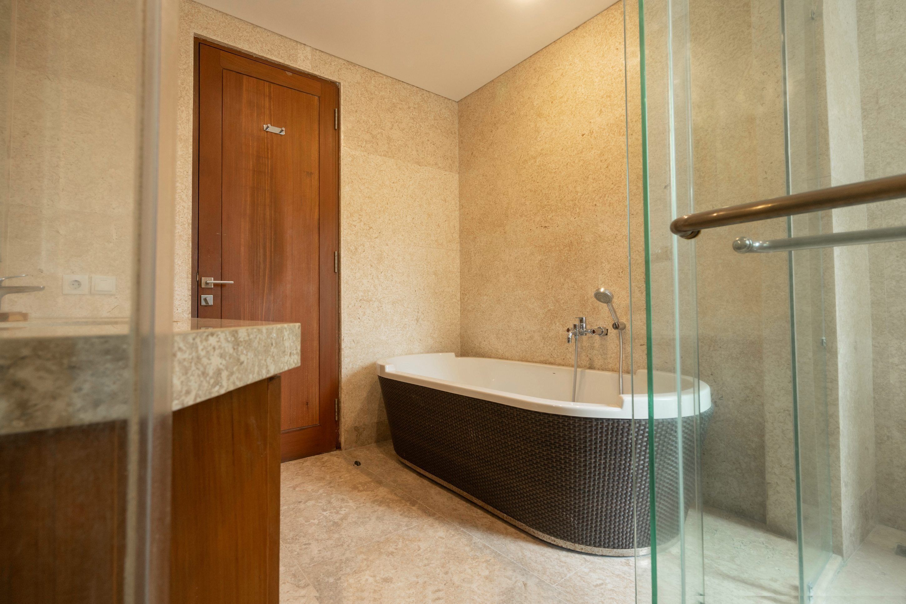 Un baño moderno con una bañera independiente, una puerta de madera y un box de ducha de vidrio.
