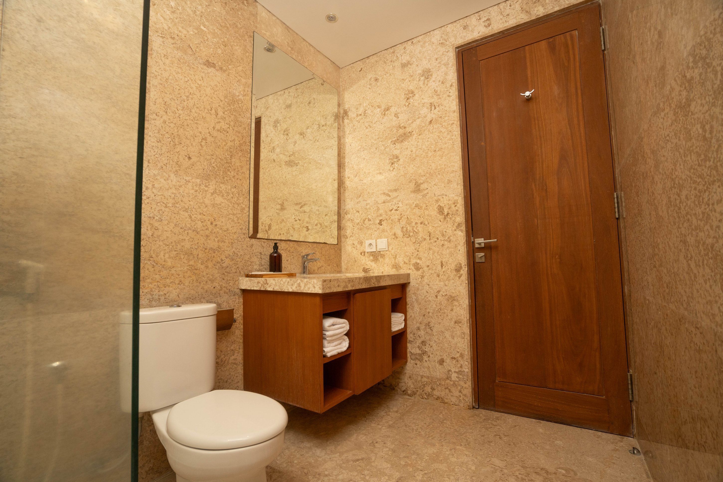 Ein Badezimmer mit Toilette, Holzkosmetikschrank und Spiegel.
