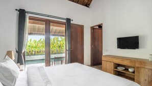 A bedroom with a large bed, a wooden dresser, a flat-screen TV, and a sliding glass door leading to a pool area. - Rarama Living Studio (Kerobokan Kaja)